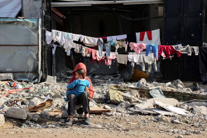 Palestinian children sit in front of a line of laundry in front of a damaged building in the Shujaiya neighbourhood in the northern Gaza Strip. (Photo: Omar AL-QATTAA/AFP)